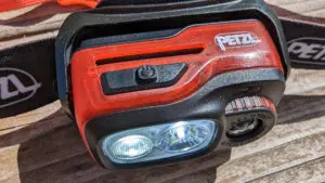 petzl-swift-rl-8 Funktionstaster für die Modi der Swift RL an der Oberseite. Dahinter ist ein Belüftungsschlitz zu sehen, der den Leuchtkörper vom Akku trennt.